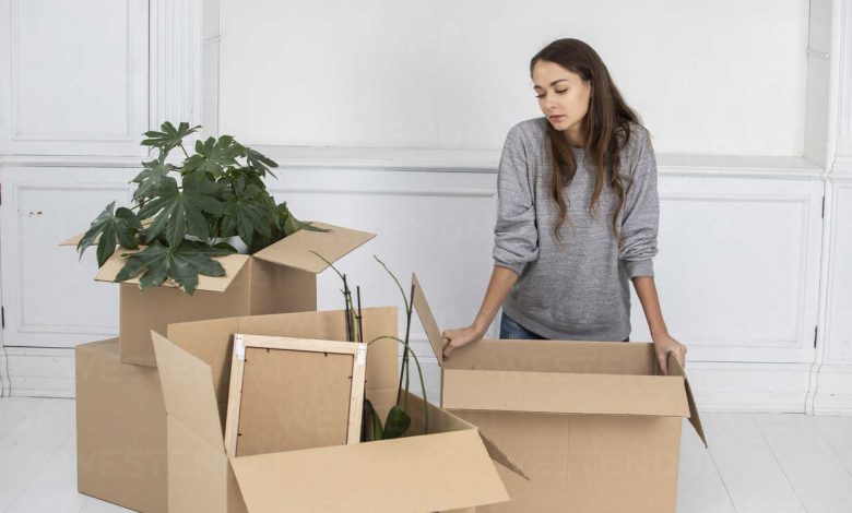 Woman standing in new home with cardboard boxes